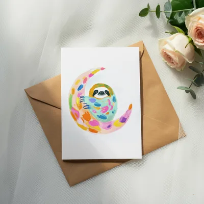 Sloth on a colorful crescent moon, on a brown envelope and roses.