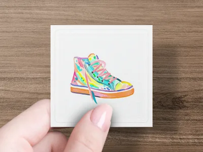 Colorful high-top sneaker illustration on a white card held by a hand.
