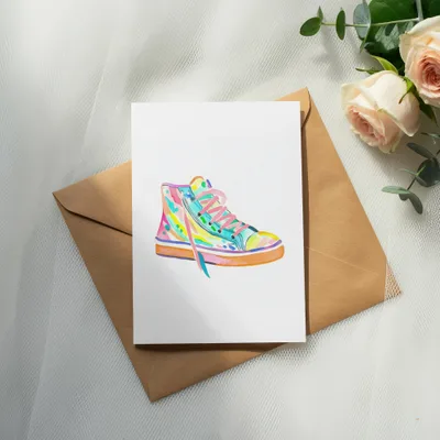 Watercolor painting of a colorful high-top sneaker on a card.