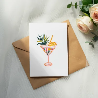Watercolor cocktail in a patterned glass with straw and fruit garnish.