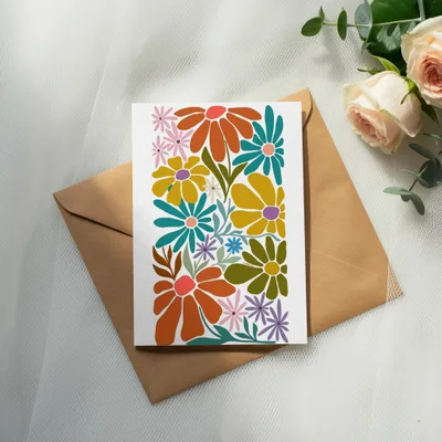 Card with colorful floral design on brown envelope, with roses and eucalyptus.