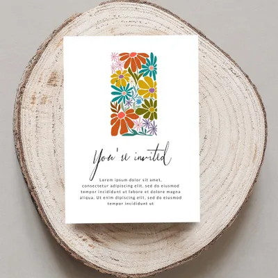 Invitation card with "You're invited" text and floral design on wood slice.