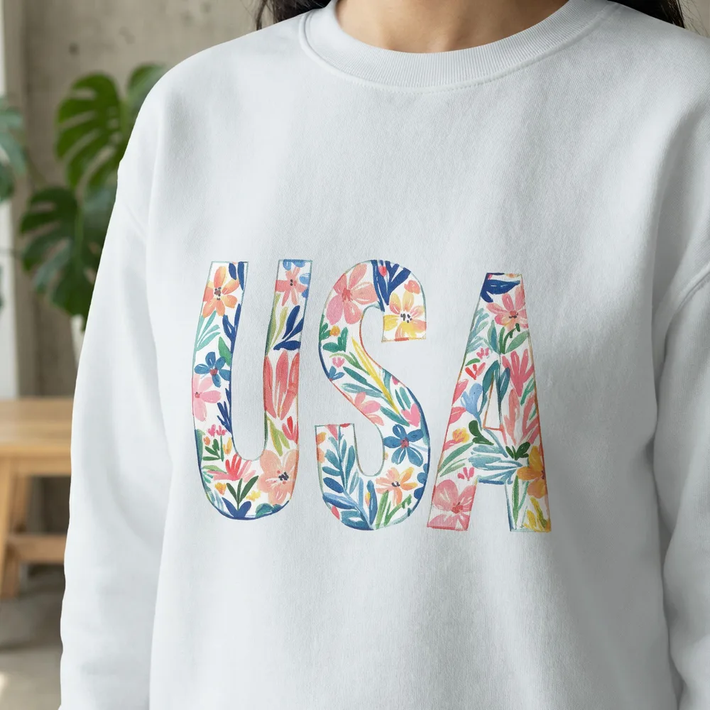 White sweatshirt with "USA" in colorful floral watercolor letters.
