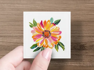 Hand holding square card with vibrant floral painting of a dahlia.