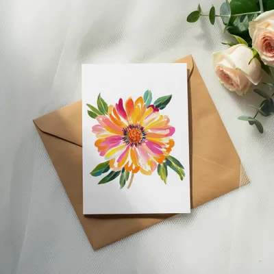 Watercolor painting of a vibrant orange and pink flower on a white card, resting on an envelope.