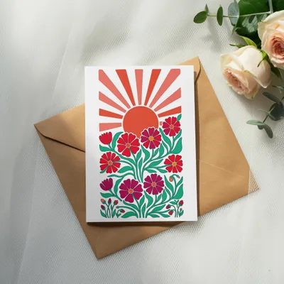 Card with red flowers and a rising sun on a brown envelope.