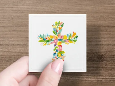 Floral cross design on a white card held by a hand.