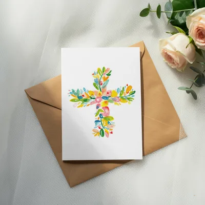 Card with colorful floral cross design on brown envelope, with roses and eucalyptus.