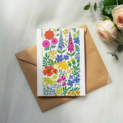 Card with colorful floral pattern on a brown envelope with roses and eucalyptus.
