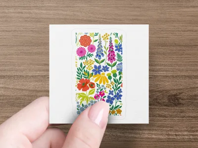 Floral sticker with pink, blue, yellow, and red flowers held by fingertips.