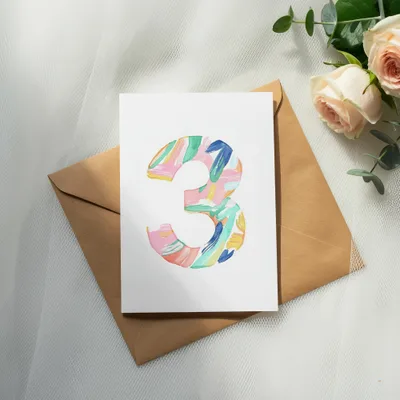 Card with colorful abstract number 3 on brown envelope, with roses.