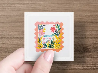 Hand holding a square sticker with a floral and leaf design.