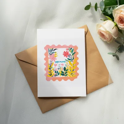 Card with colorful floral border on brown envelope, with roses and eucalyptus.