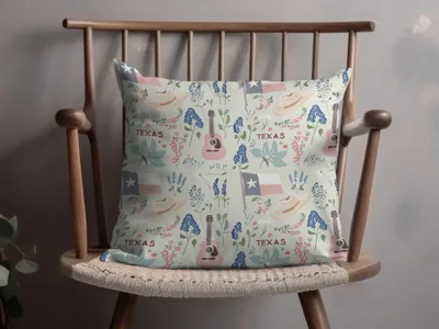 Texas-themed throw pillow with flags, guitars, hats, and flowers on a chair.