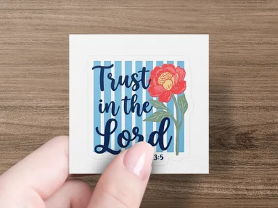 Square sticker with "Trust in the Lord" and flower, held by a hand.