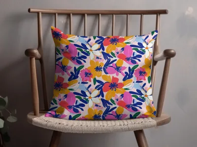 Floral print pillow with pink, blue, yellow, and white flowers on a light pink background.