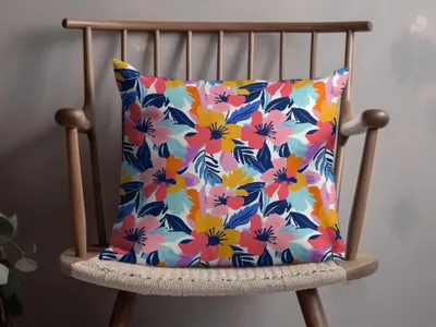 Floral pillow with pink, blue, and yellow flowers on white background.