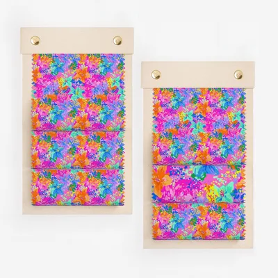 Two fabric swatches with vibrant floral patterns on wooden boards.