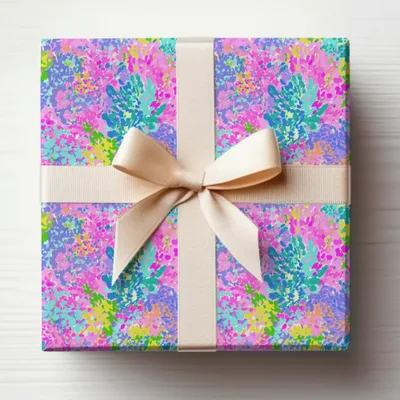 Gift-wrapped box with a colorful abstract floral pattern and cream ribbon bow.