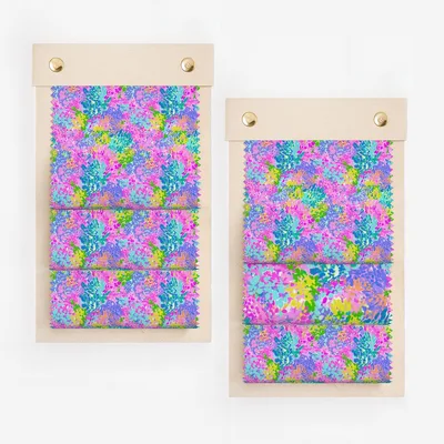 Two fabric swatches with a vibrant floral pattern in pink, blue, and yellow.
