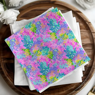Colorful abstract splatter pattern on napkins stacked on a wooden tray.