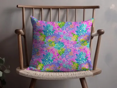 Brightly colored floral pattern on a throw pillow on a wooden chair.