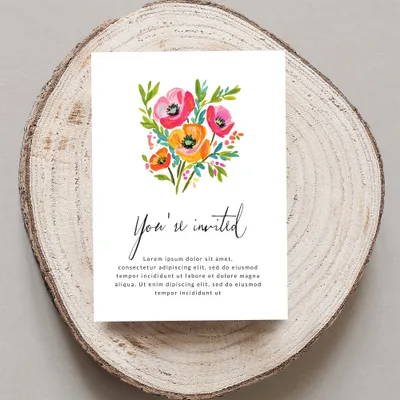 Invitation with "You're invited" and floral illustration on wood slice.