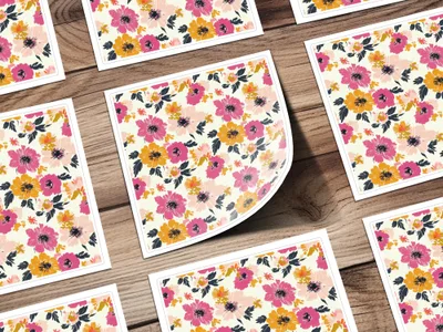 Scattered floral patterned cards with pink, orange, and yellow flowers on wood.