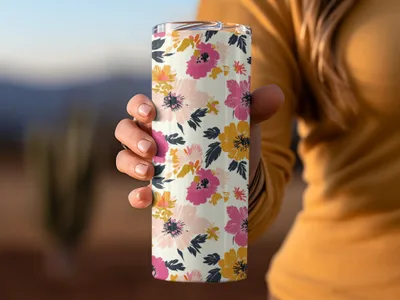 Hand holding a floral patterned tumbler with pink, yellow, and coral flowers.