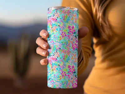 Tumbler with colorful floral pattern held by a person.