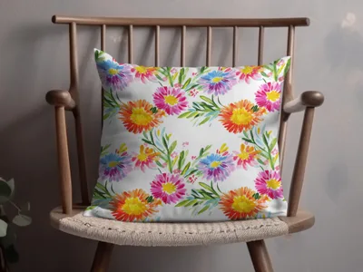 Pillow with colorful floral watercolor pattern on a wooden chair.