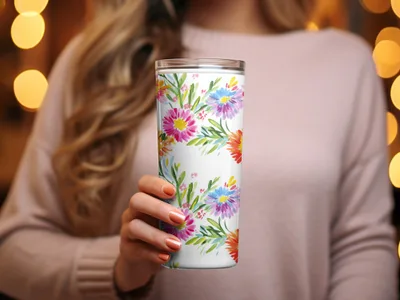 Woman holding a white tumbler with a colorful floral pattern.