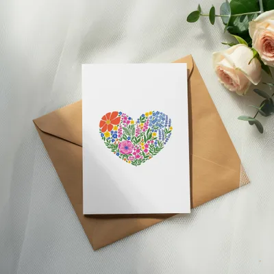 Blank card with colorful floral heart design on brown envelope.