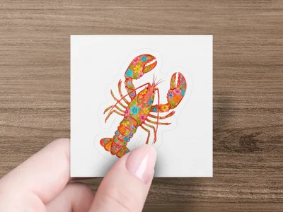 Lobster sticker with floral pattern on white surface held by fingers.