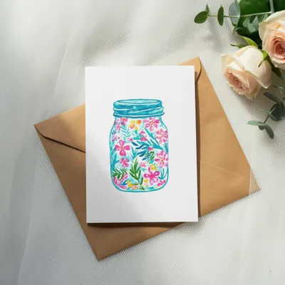Card with watercolor floral design inside a mason jar on brown envelope.