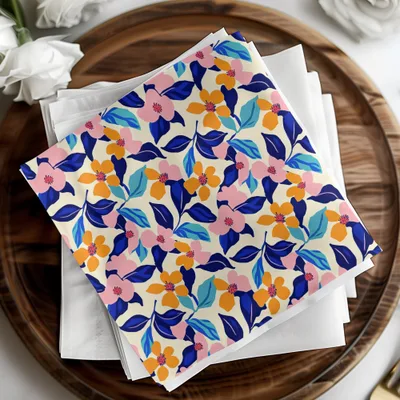 Folded fabric napkins with a colorful floral pattern on a wooden tray.