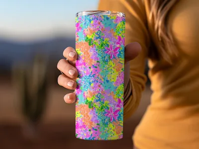 Tumbler with colorful abstract floral pattern held by hand.