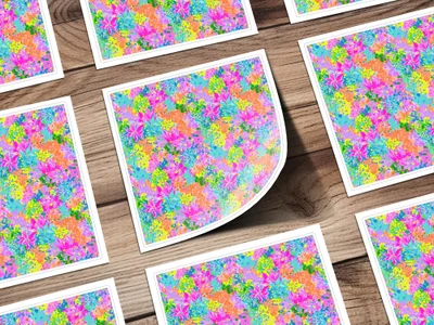 Colorful floral pattern on multiple square cards, some overlapping, on a wooden surface.