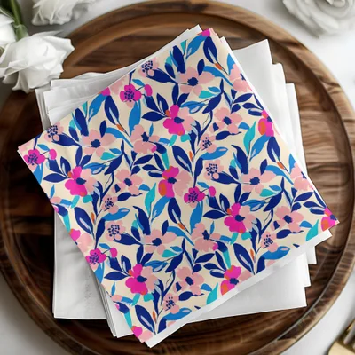 Beige paper napkins with a vibrant pink, blue, and green floral pattern.
