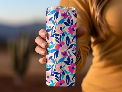 Hand holding floral patterned tumbler with blue, pink, and cream flowers.