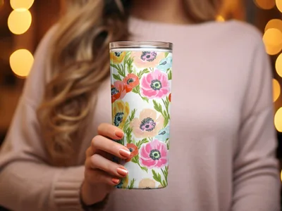 Woman holding tall tumbler with floral pattern featuring poppies and other flowers.