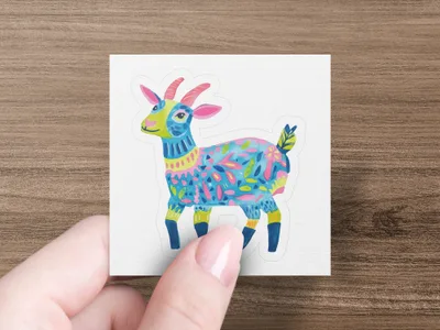 Colorful, patterned goat sticker held by a person's fingers.