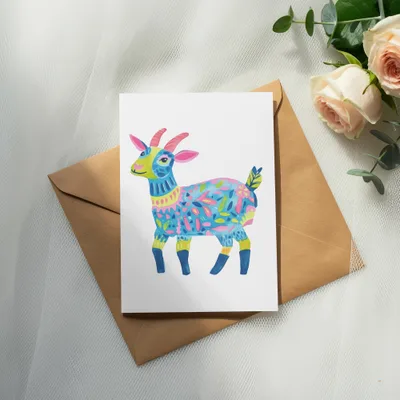 Watercolor illustration of a colorful, patterned goat on a greeting card.