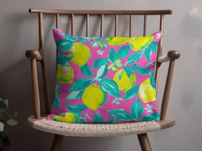 Pink pillow with a bright yellow lemon pattern on a wooden chair.
