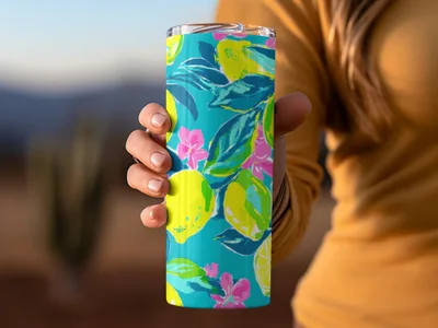 Teal tumbler with a colorful lemon and floral pattern, held by a person.