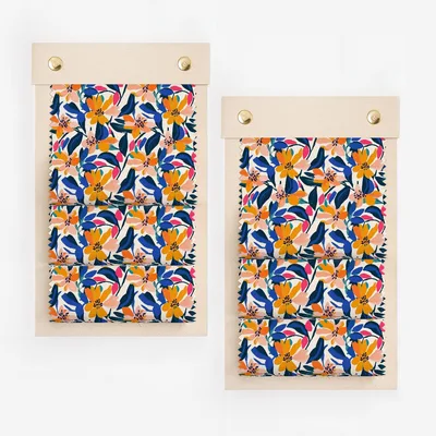 Two swatches of fabric with a colorful floral pattern on wooden clips.