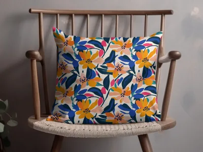 Decorative throw pillow with a vibrant floral pattern in orange, blue, and pink on a cream background.