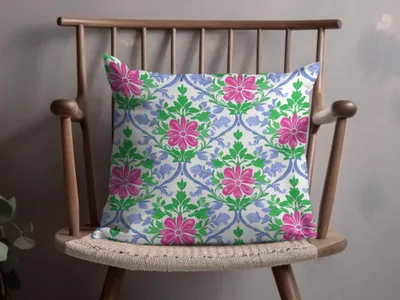 Throw pillow with pink floral and green leaf pattern on a wooden chair.