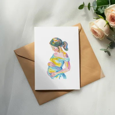 Watercolor painting of a pregnant woman on a card, placed on a brown envelope.