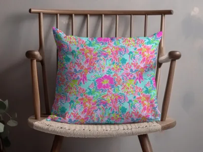 Bright floral pattern pillow on a wooden chair.